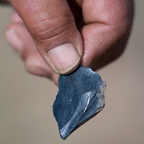 Myron Smart, a member of the Fort McDermitt Paiute and Shoshone tribe, displays a piece of obsidian, or volcanic rock, near Sentinel Rock on April 25, 2023, outside of Orovada, Nev. Similar rocks were used to make tools such as arrowheads or spearheads by Smart's ancestors. Pieces of obsidian rock can be found at Sentinel Rock, a sacred site for the Paiute and Shoshone tribes. (AP Photo/Rick Bowmer)